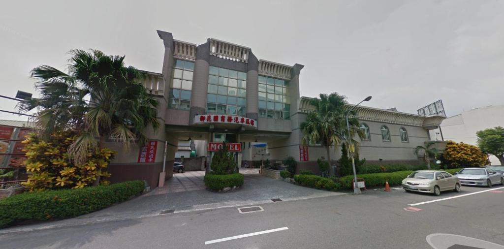 un gran edificio con coches estacionados frente a él en 雲林斗六御花園汽車旅館, en Douliu