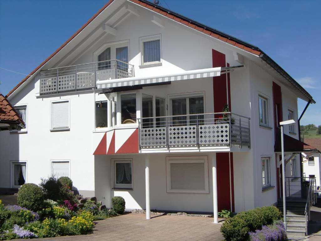 a white and red house with a balcony at Haus Fechtig in Bonndorf im Schwarzwald