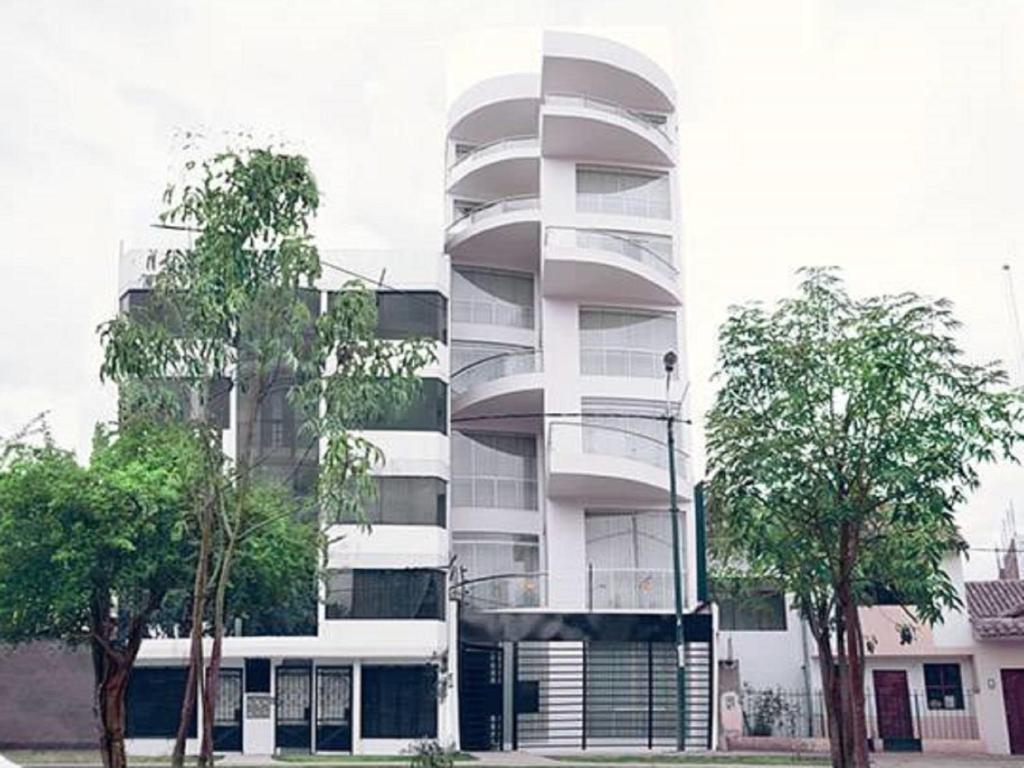 un edificio alto y blanco con árboles delante en Parque 5, en Cusco