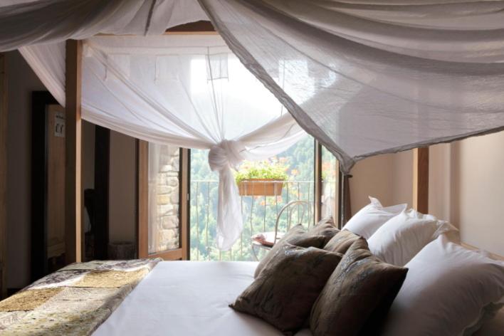 a bedroom with a canopy bed with a window at El Acebo de Casa Muria in Bisaurri