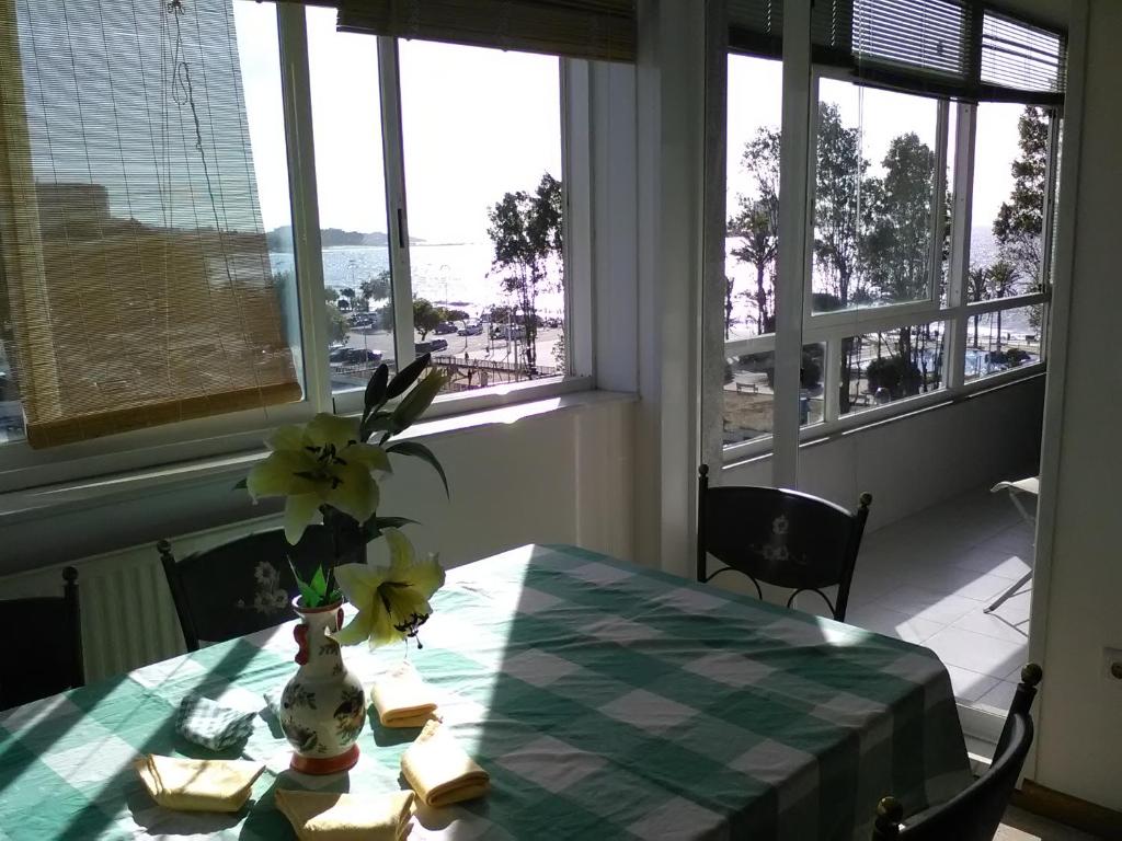 una mesa con un jarrón de flores encima en Apartamento playa Samil en Vigo