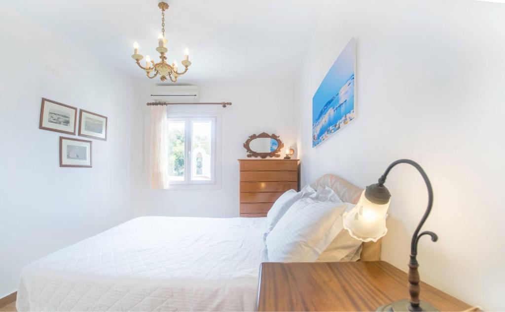 a white bedroom with a bed and a lamp at New Mykonos town house in Mikonos
