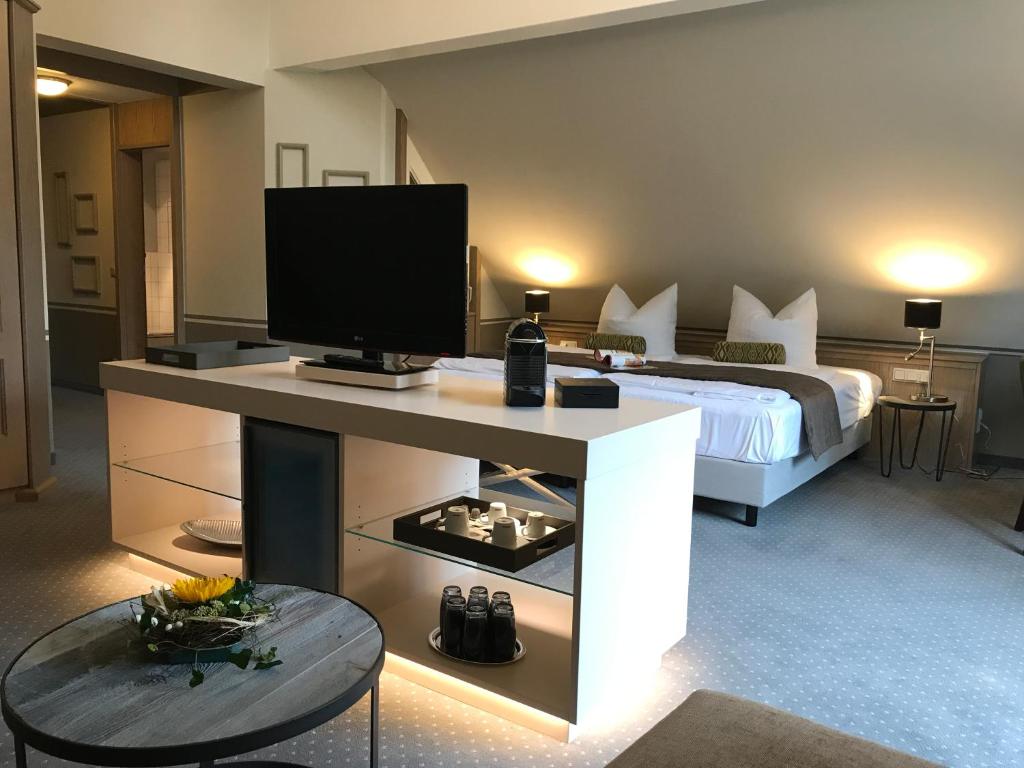 ein Schlafzimmer mit einem Bett und einem TV auf dem Tisch in der Unterkunft Romantisches Hotel Menzhausen in Uslar