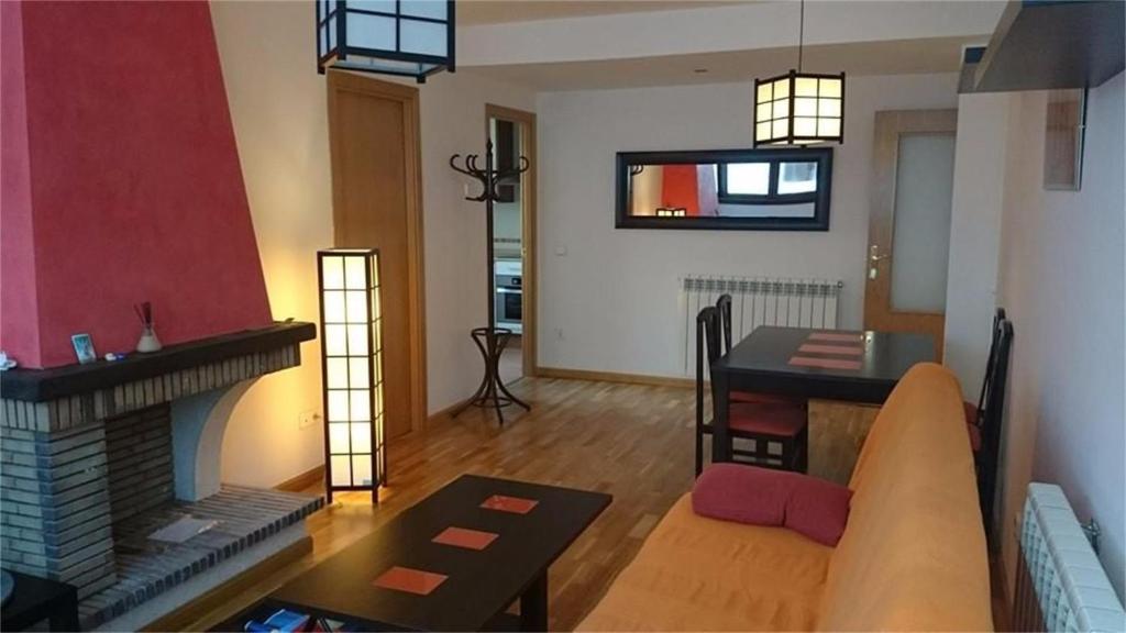 a living room with a fireplace and a dining room at Apartamento Nicomar in Escarrilla