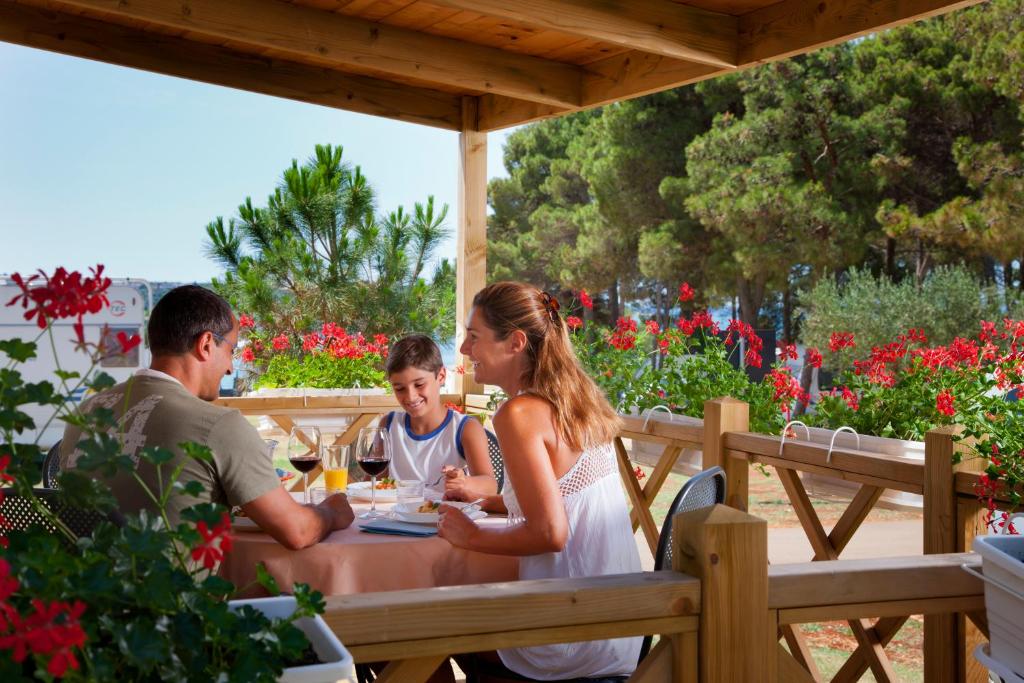 een gezin aan een tafel in een restaurant bij Sirena Mobile Homes in Novigrad Istria