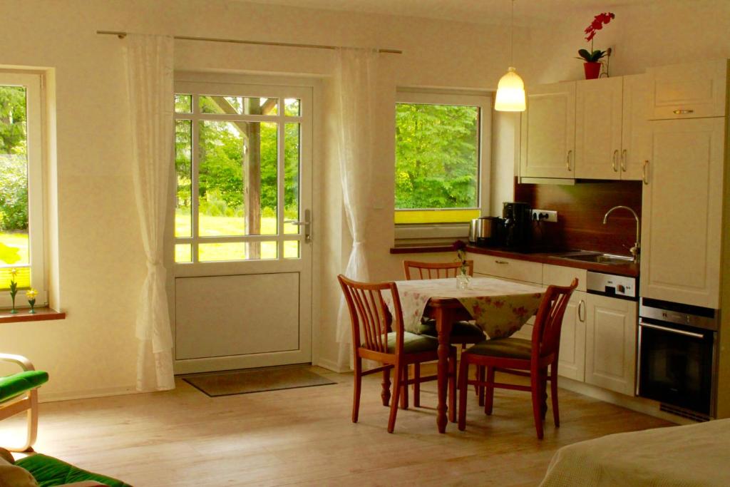 eine Küche mit einem Tisch, Stühlen und Fenstern in der Unterkunft Ferienwohnung Vogelsang in Süderhöft