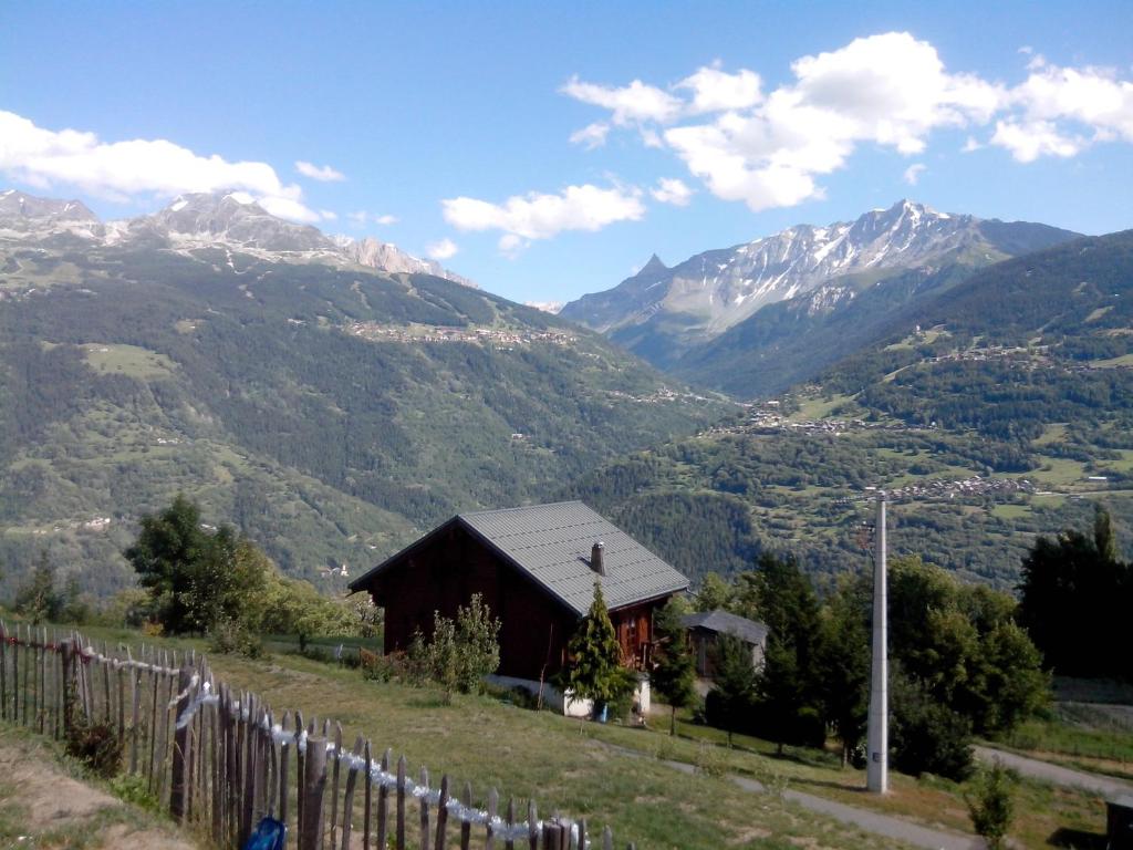 a barn on a hill with mountains in the background at Spacieux Chalet in Les Chapelles