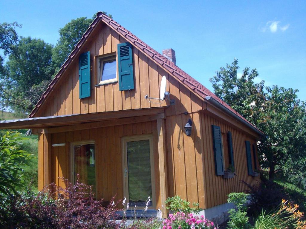 a wooden house with blue shutters on it at Ferienhaus Henke in Hohnstein