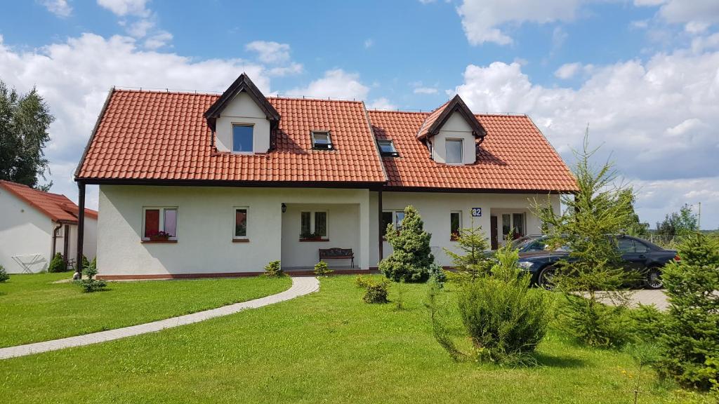 ギジツコにあるGościniec Mazurekのオレンジ色の屋根と庭のある白い家
