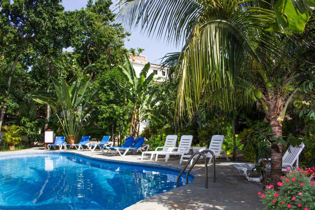 a swimming pool with lounge chairs and a palm tree at Residencial Estephany in Sosúa