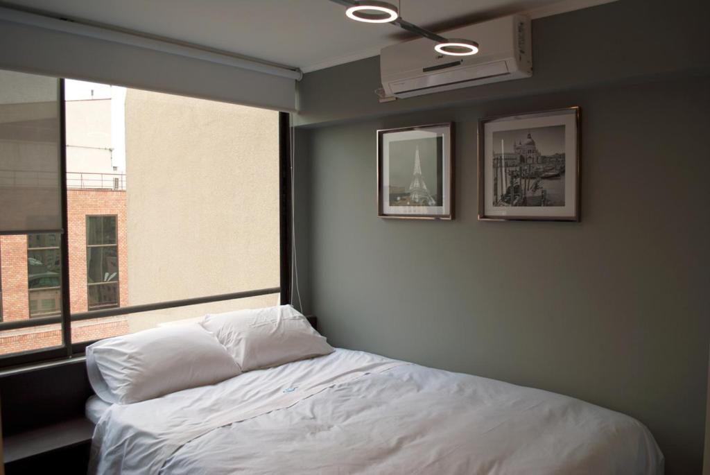 a bedroom with a white bed and a window at Amg Apartments in Santiago