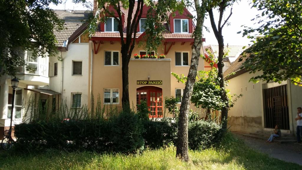 a building with a red door in a yard at Stop Panzio in Debrecen