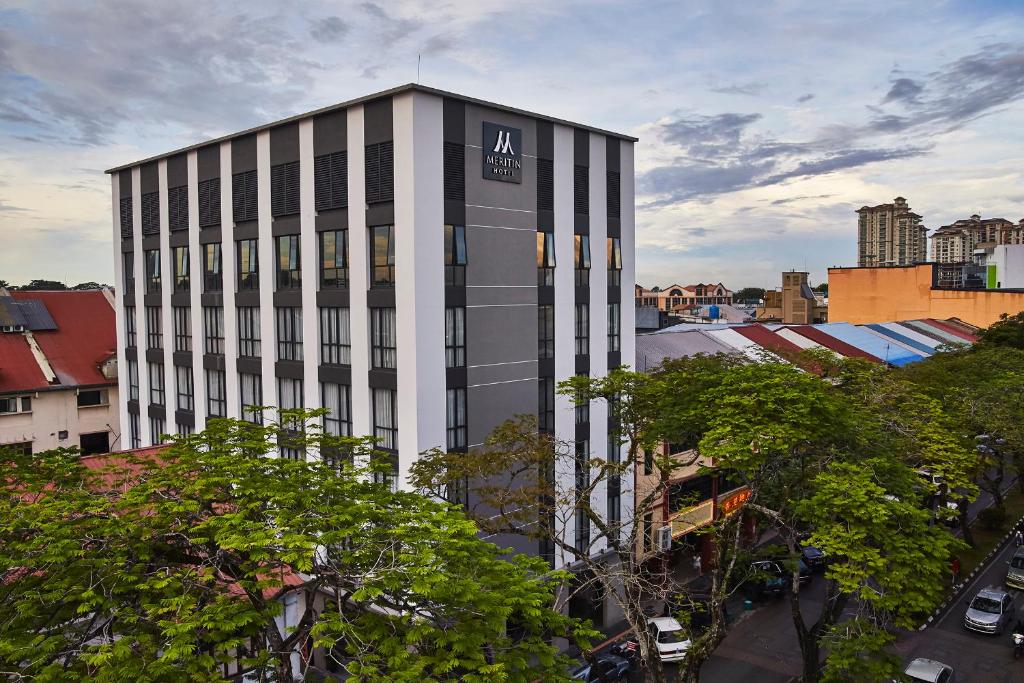 un grand bâtiment avec un panneau sur son côté dans l'établissement Meritin Hotel, à Kuching