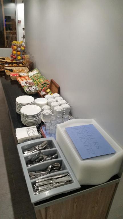 a counter with plates and utensils on top at Kyriad Cambrai in Cambrai