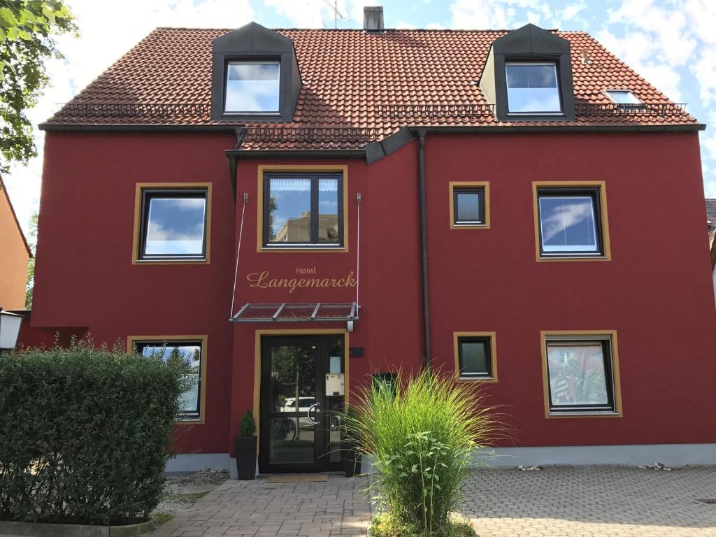 a red house with a red roof at Hotel Augsburg Langemarck in Augsburg