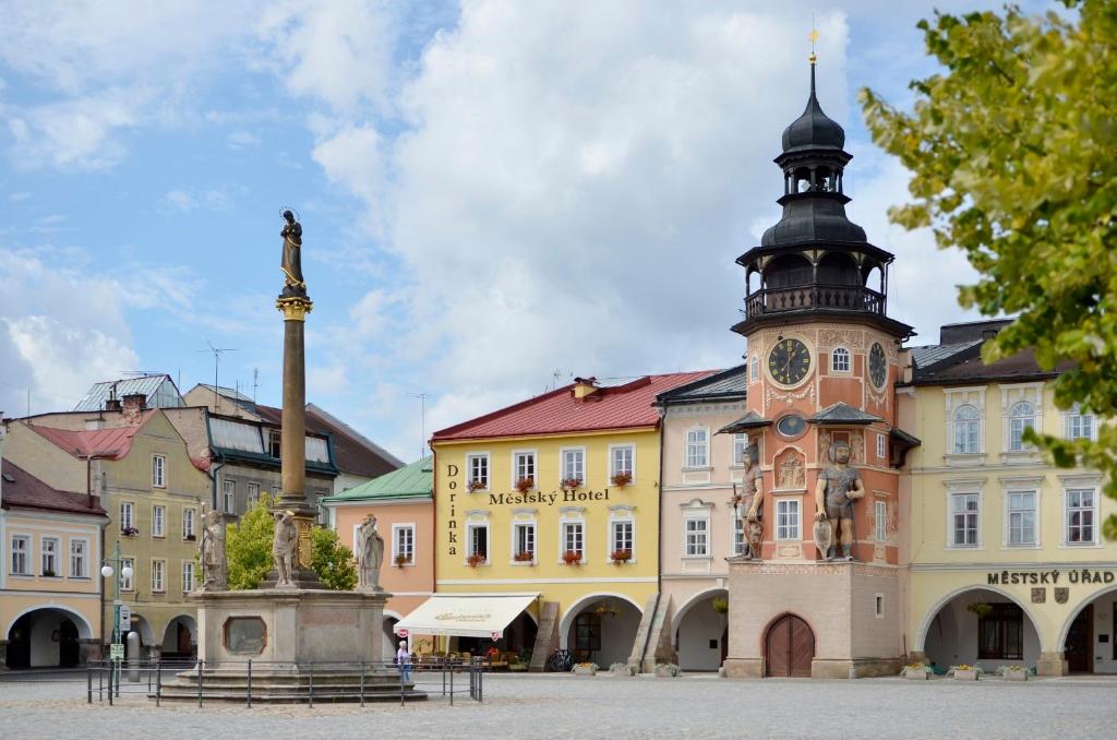 a building with a clock tower in front of it at Městský Hotel Dorinka in Hostinné