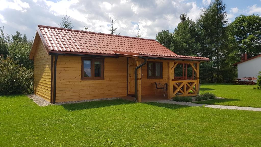 Cabaña de madera pequeña con techo rojo en Gościniec Mazurek , Domek drewniany 1 en Giżycko