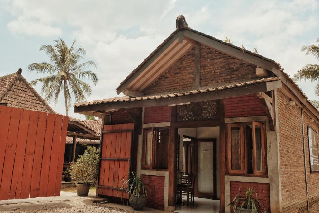 a small house with a palm tree in the background at Cempaka Borobudur Guest House in Borobudur