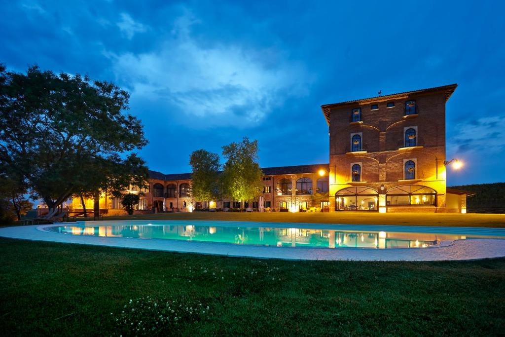 a large building with a pool in front of it at night at Tenuta Montemagno Relais & Wines in Montemagno