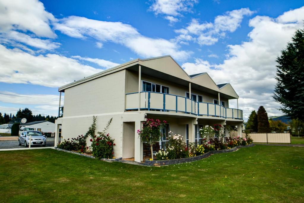 a white house with a balcony on a yard at Parklands Motel in Te Anau