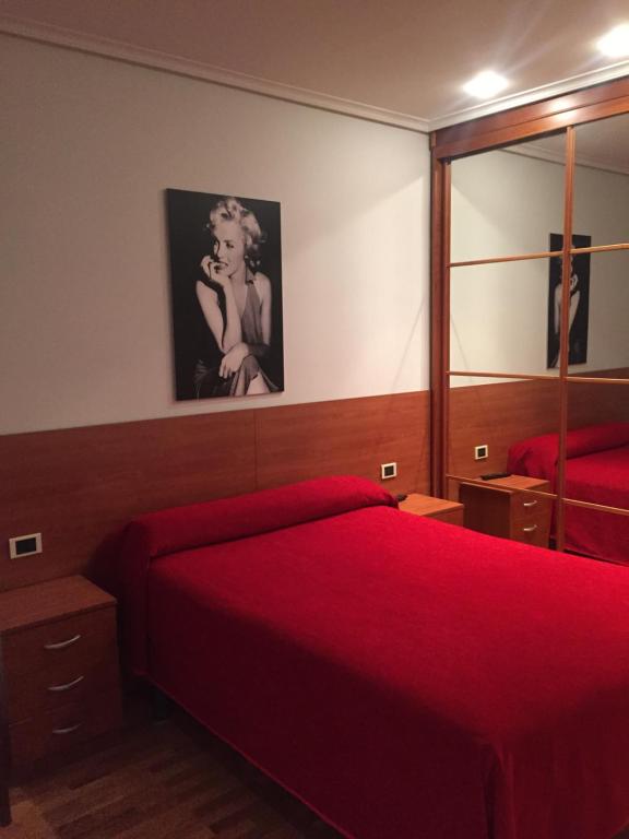 a bedroom with a red bed and a mirror at Pension Logroño in Logroño
