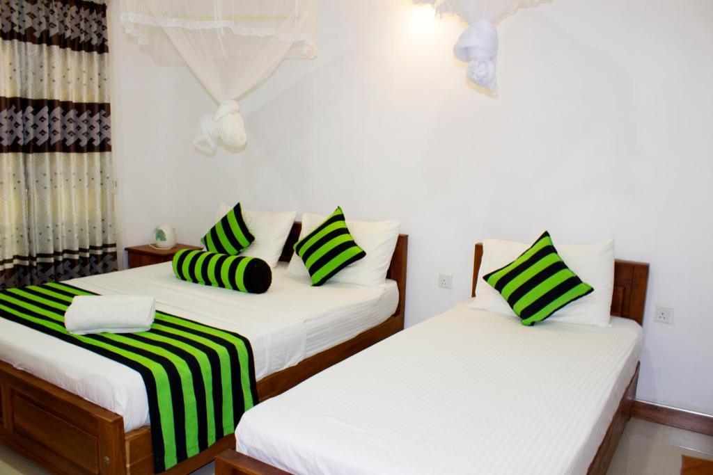 two beds in a room with white and green striped pillows at Sigiri Leisure Holiday Home in Sigiriya