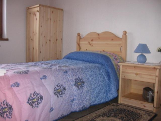a bedroom with a bed with a wooden headboard and a table at B&B Edelweiss in Oulx