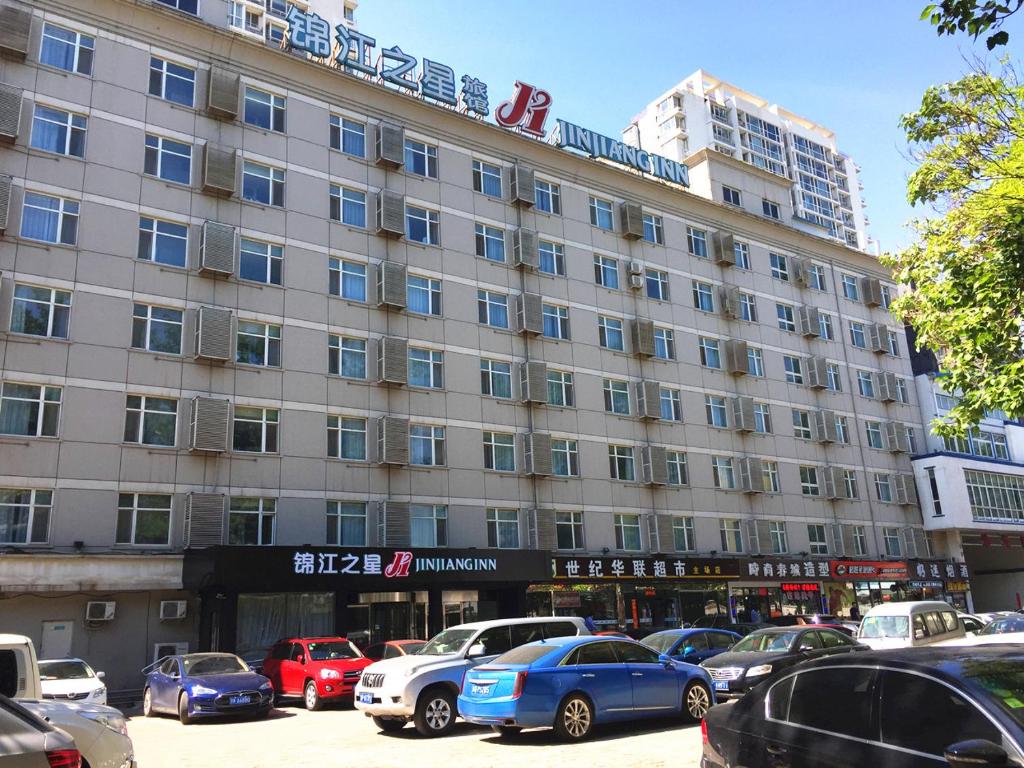 un grande edificio con auto parcheggiate in un parcheggio di Jinjiang Inn - Beijing Olympic Village Datun Road a Pechino
