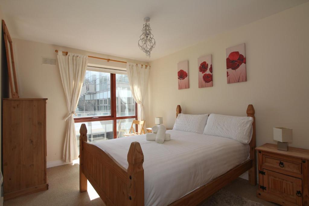 ダブリンにあるNorth Docklands Self Catering apartmentのベッドルーム1室(白いシーツ付きのベッド1台、窓付)