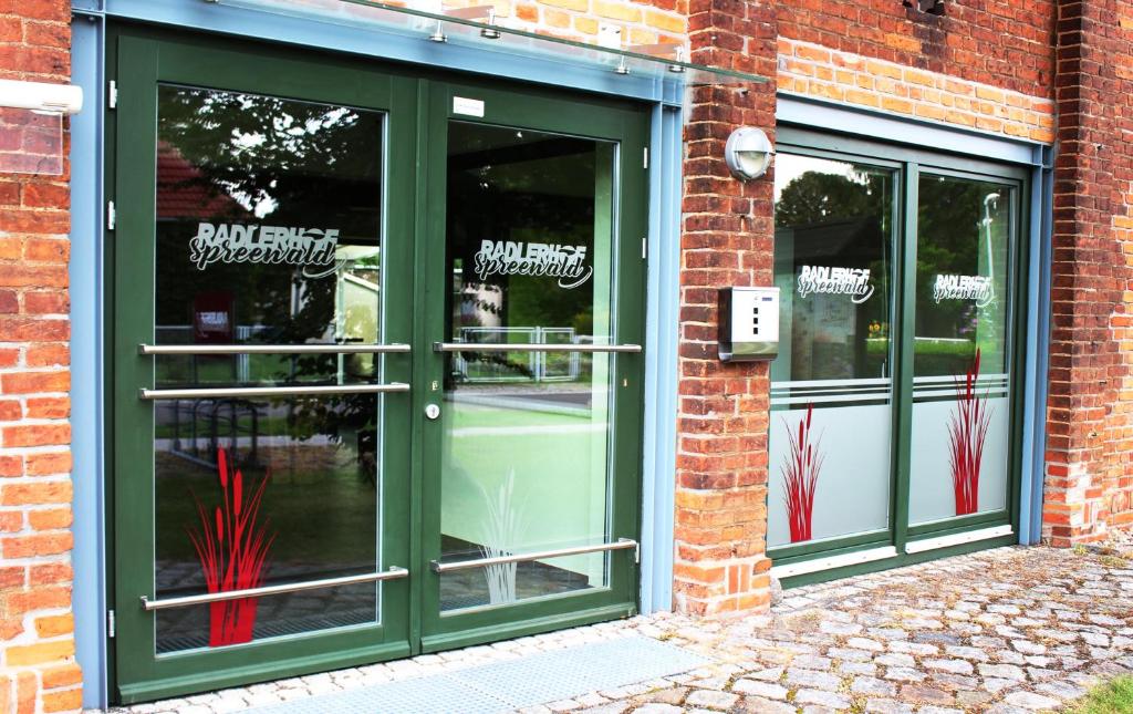 a store with green doors on a brick building at Radlerhof Spreewald in Kolkwitz