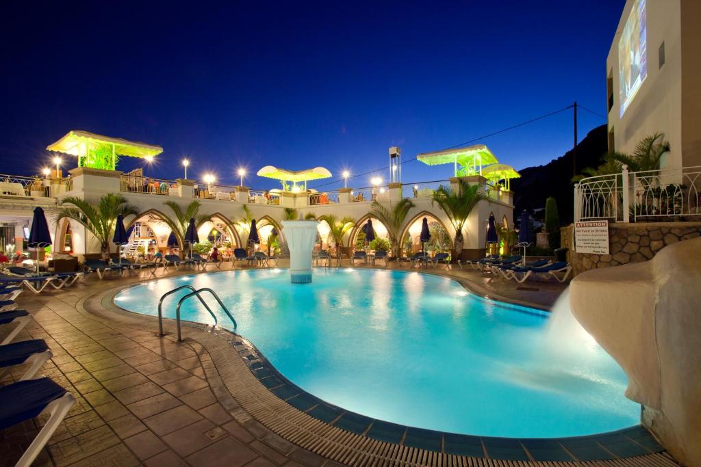 a large swimming pool in a hotel at night at Pefkos Beach Studios & Apartments in Pefki