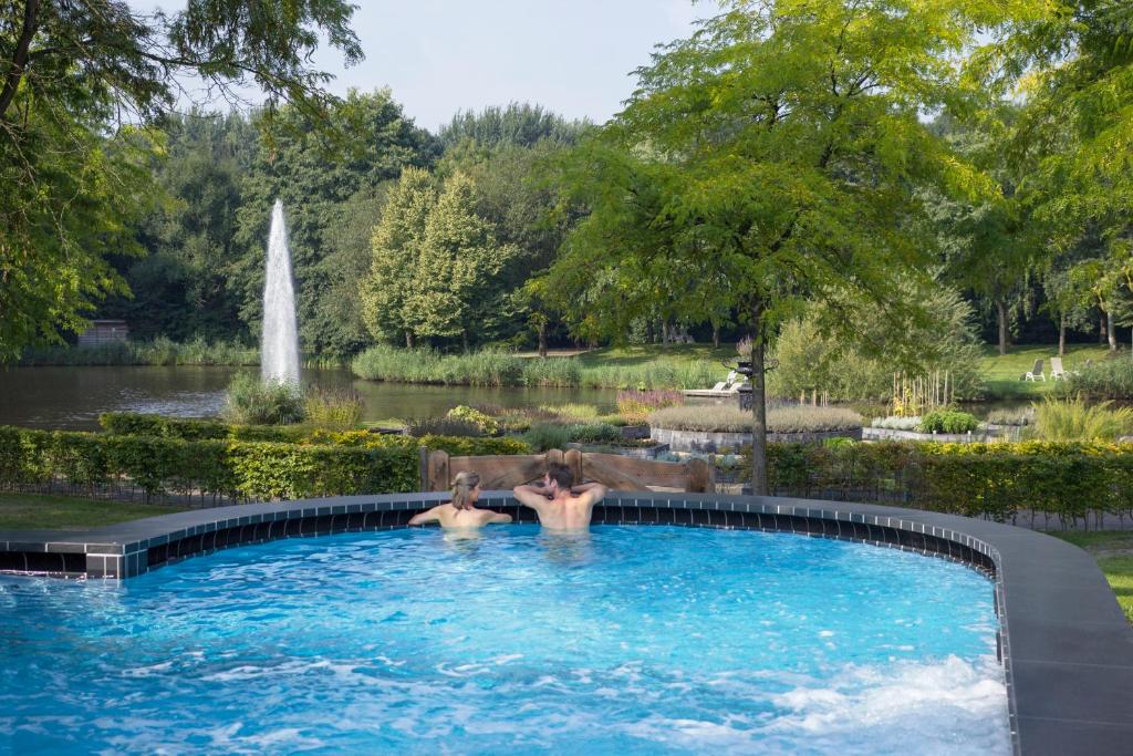 dos personas en una piscina en un jardín con una fuente en Thermen Bad Nieuweschans, en Bad-Nieuweschans