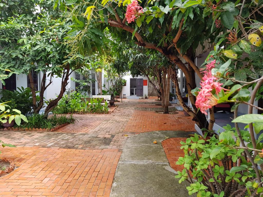 a brick walkway with trees and flowers on it at Cay Phuong Guesthouse in Mui Ne