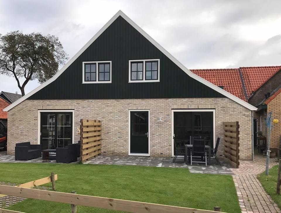 a house with a black roof and a yard at De beurs in Hollum