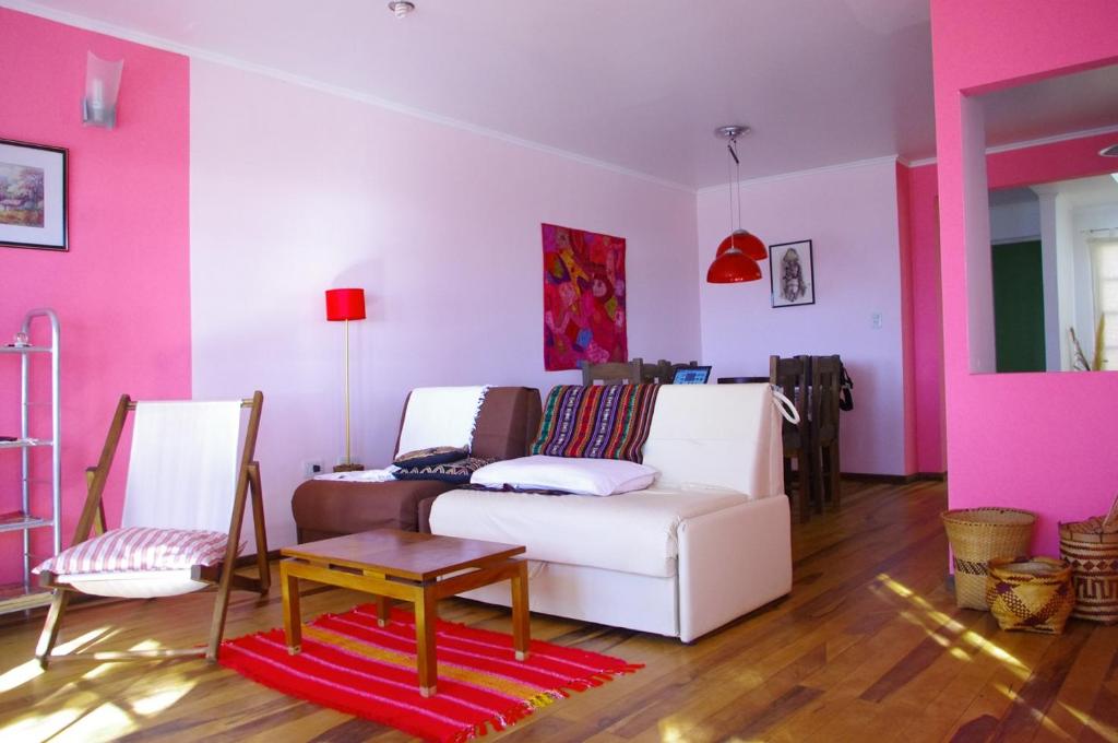 uma sala de estar com um sofá branco e paredes cor-de-rosa em Costa Aguacates em Posadas