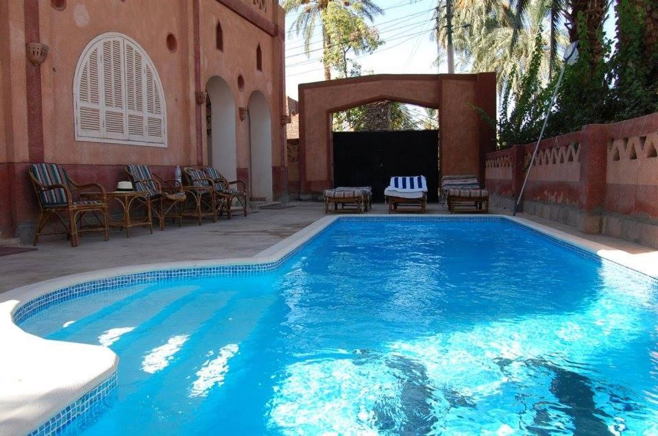 uma grande piscina azul com cadeiras e mesas em villa al diwan luxor em Luxor