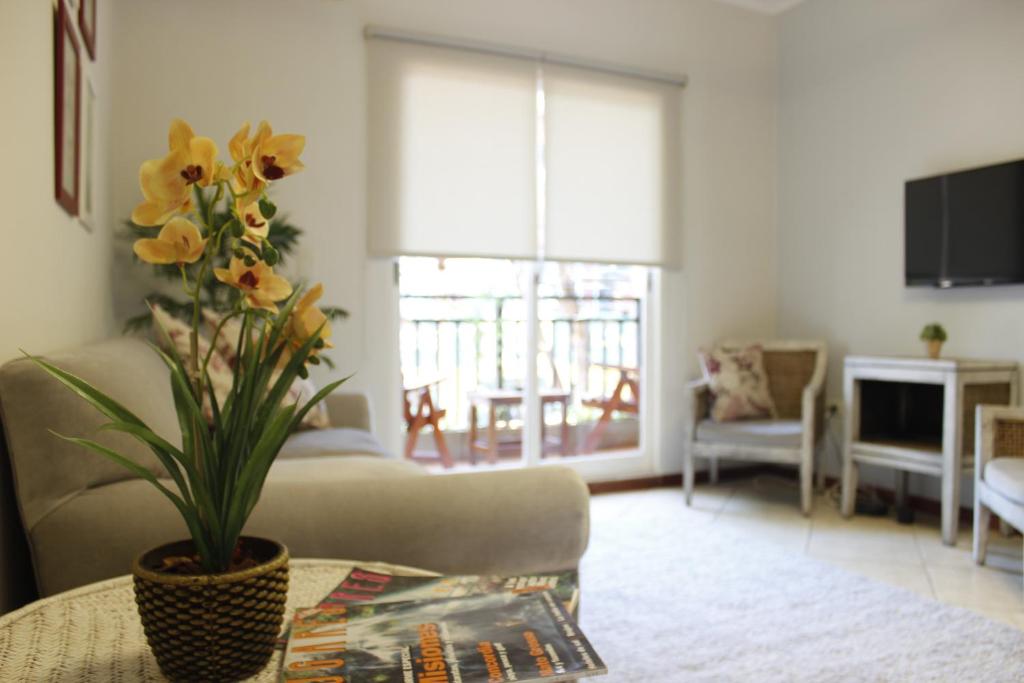 uma sala de estar com um sofá e uma mesa com flores em Flora Apartments em Puerto Iguazú