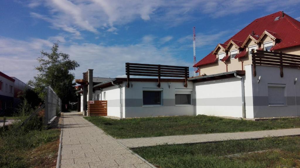 a white house with a red roof and a sidewalk at M0 Lakihegy Horgony u 10 in Szigetszentmiklós