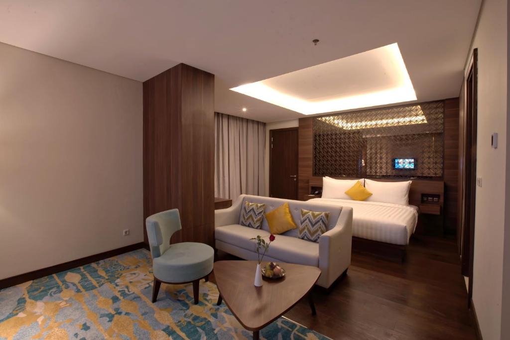 Grand Soll Marina Hotel في تانغيرانغ: غرفه فندقيه بسرير واريكه وطاولة
