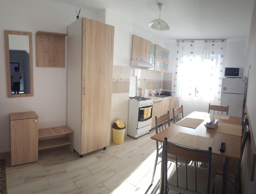 a kitchen with wooden cabinets and a table and a dining room at Apartament Lupu - Eforie Nord in Eforie Nord