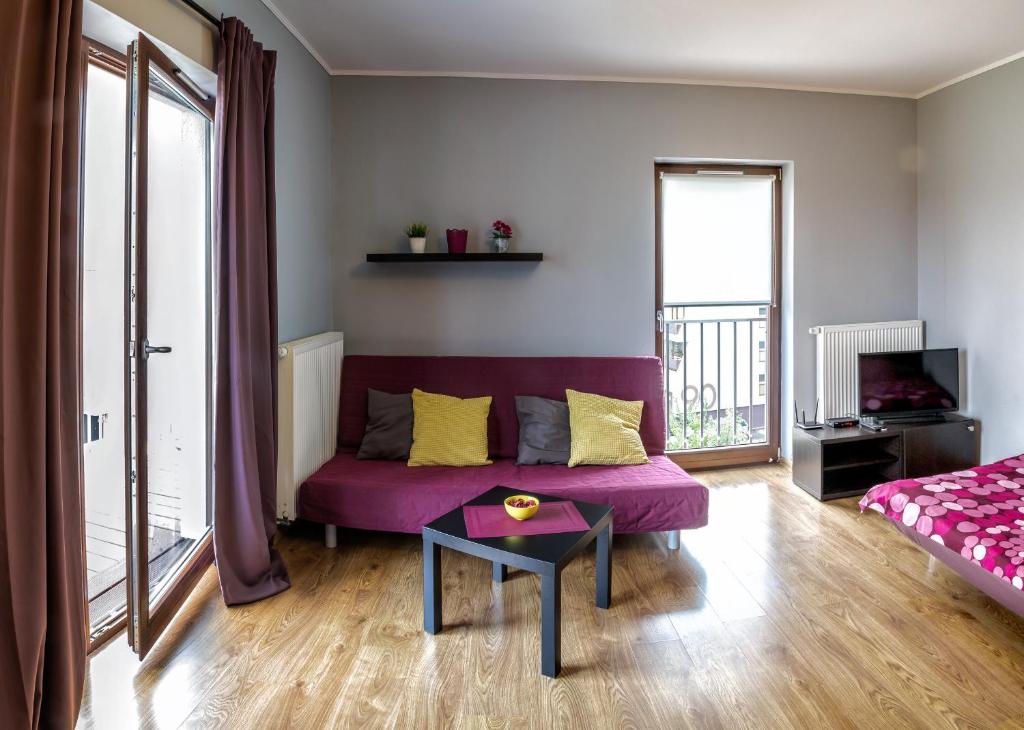 ヴロツワフにあるMarea Apartmentの紫色のソファとテーブル付きのリビングルーム