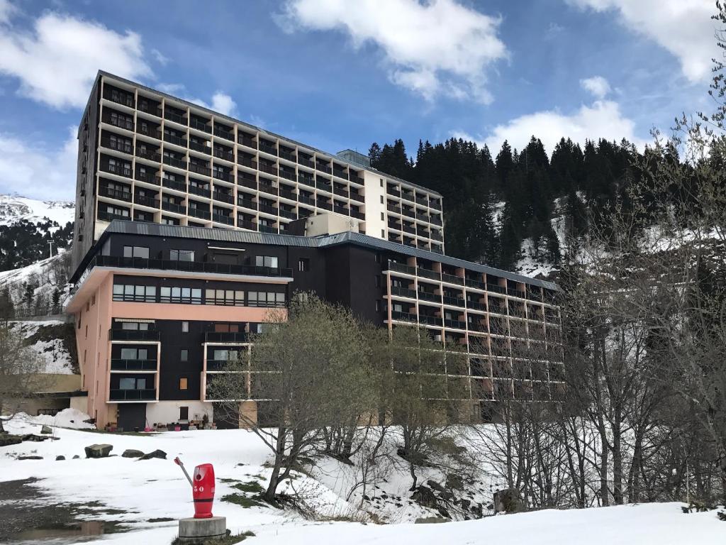 un bâtiment doté d'une bouche d'incendie rouge dans la neige dans l'établissement Appartement Chamrousse le Vernon, à Chamrousse