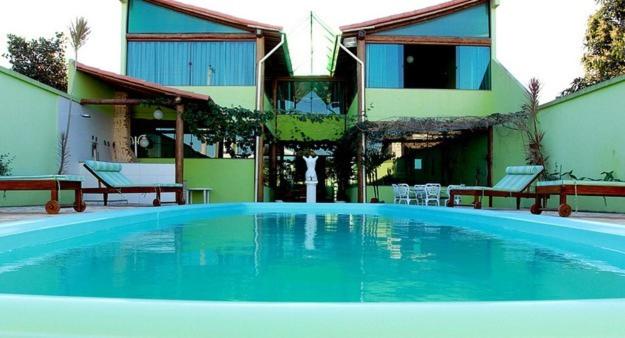 uma grande piscina azul em frente a um edifício em Pousada Luz do Sol em Rio das Ostras