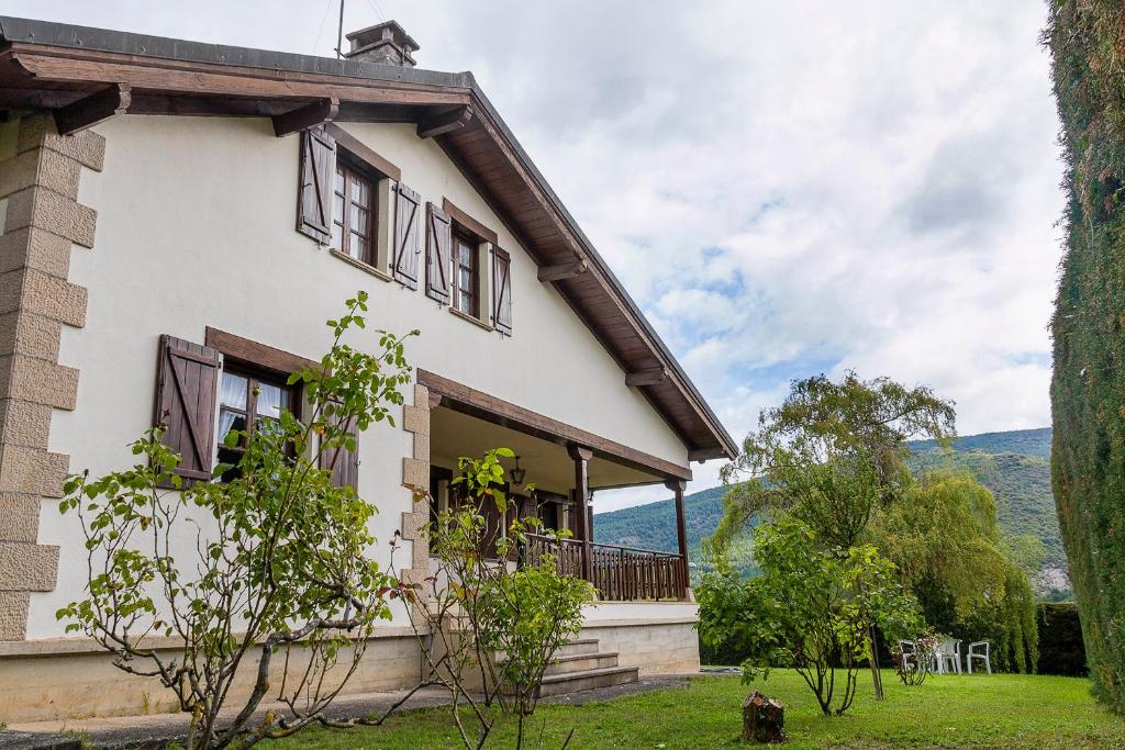 uma casa branca com varanda e montanhas ao fundo em Vivienda Rural Casa Javier Lacunza em Aoiz