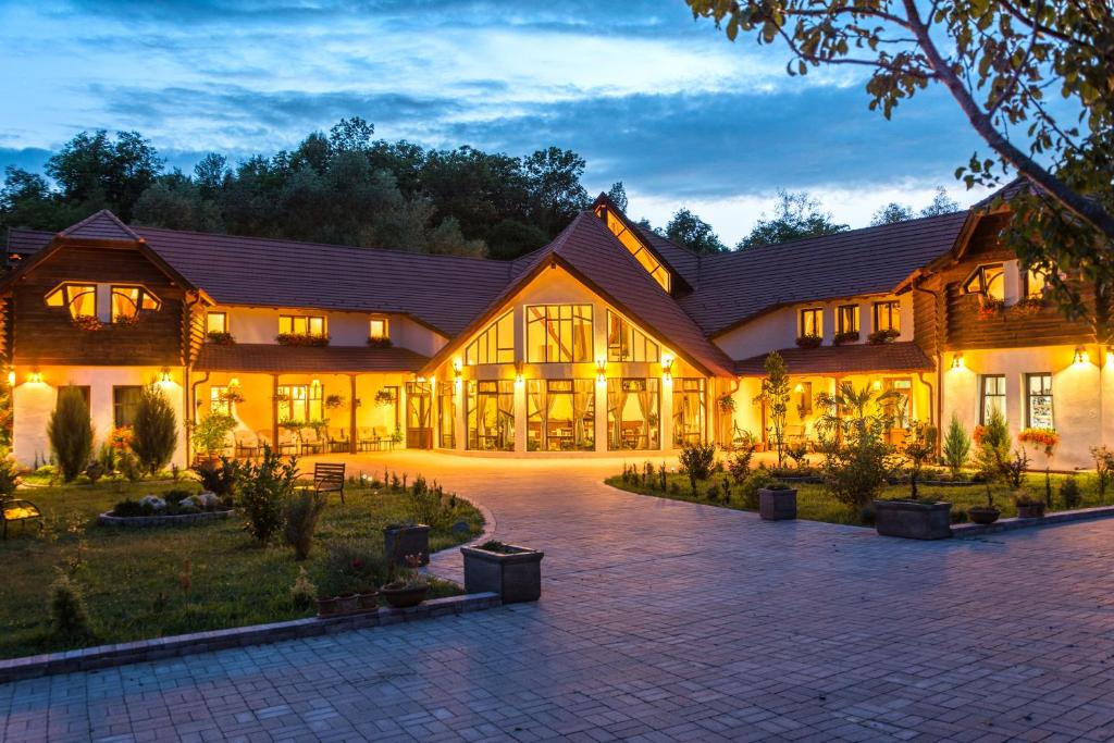 una vista esterna di un grande edificio in legno di notte di Pensiunea Meander a Gherla