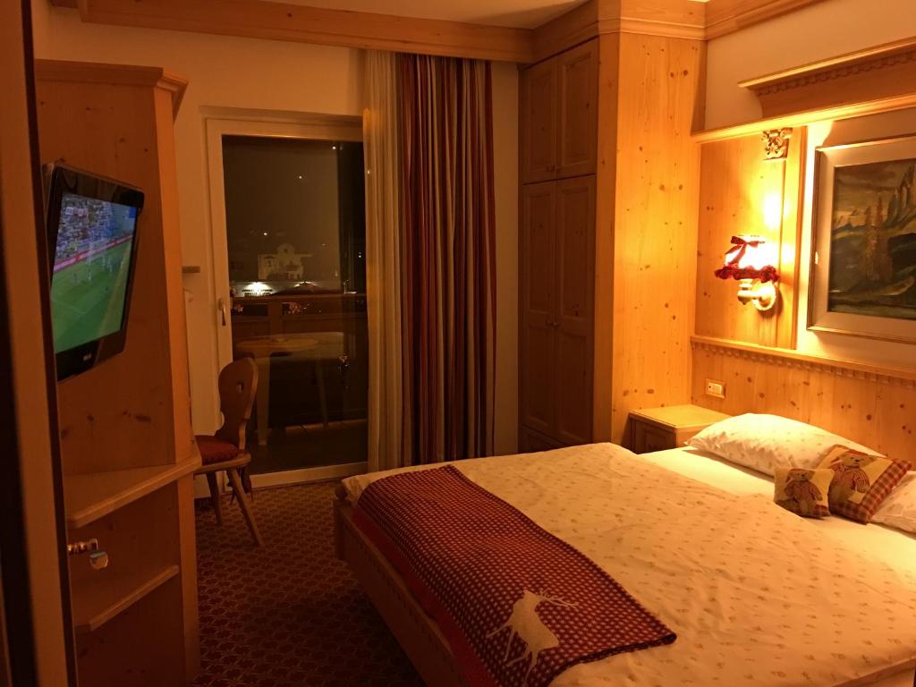 pokój hotelowy z łóżkiem i telewizorem z płaskim ekranem w obiekcie Garni Toni w mieście Ortisei