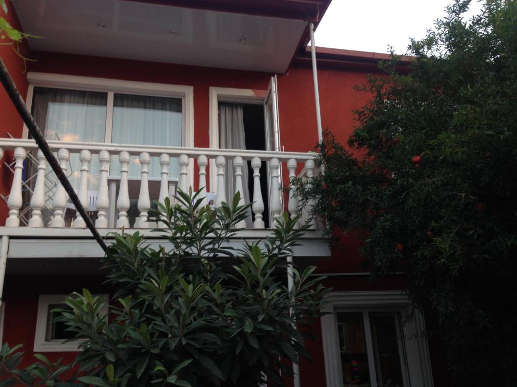 ein rotes Haus mit einem weißen Balkon und einem Baum in der Unterkunft Apartment SOFI in Tbilisi City