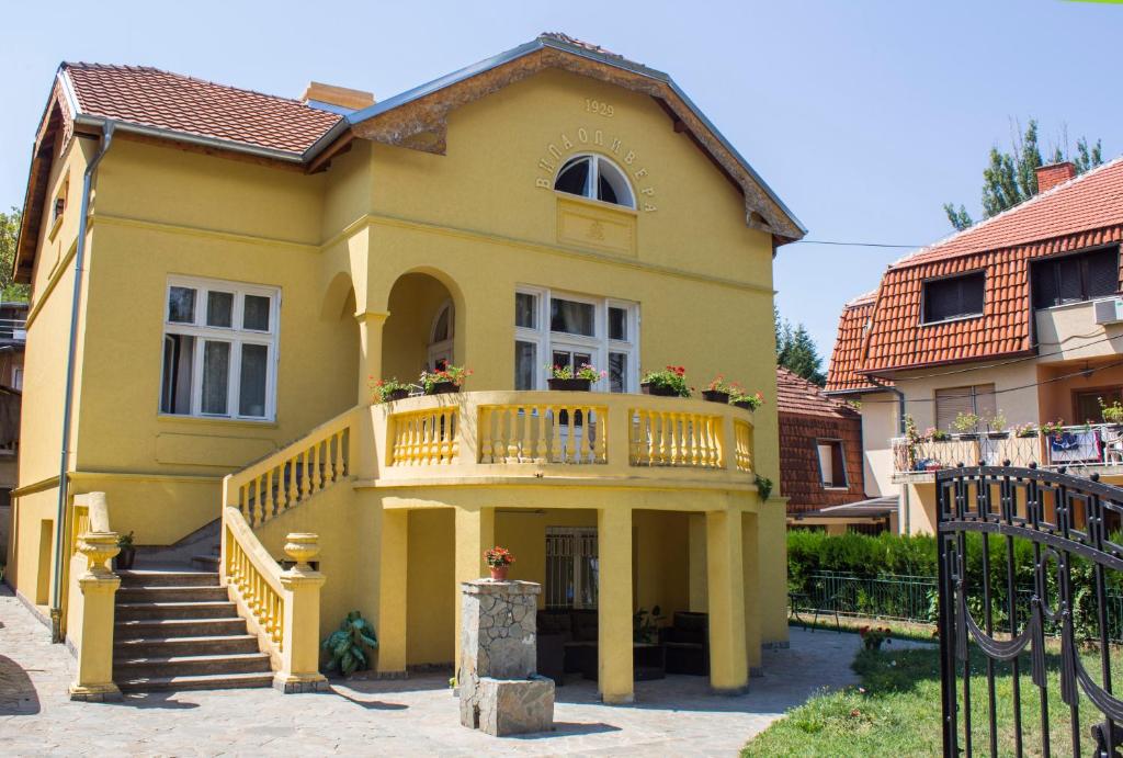 a yellow house with a balcony and stairs at Smeštaj Olivera Niška Banja in Niška Banja