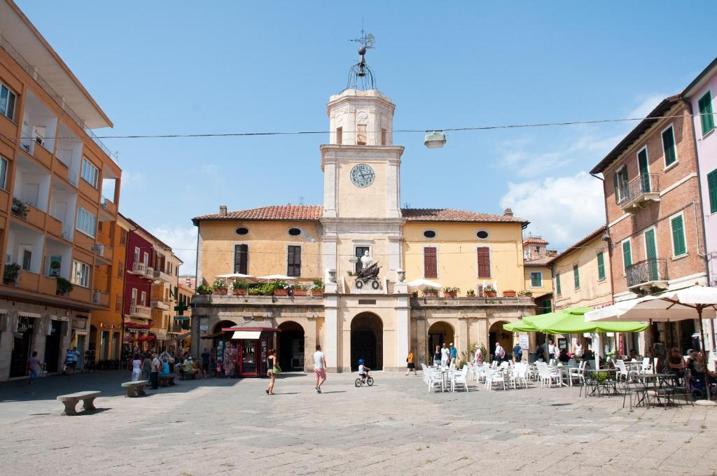 un edificio con una torre de reloj en medio de una calle en Hotel Sole en Orbetello