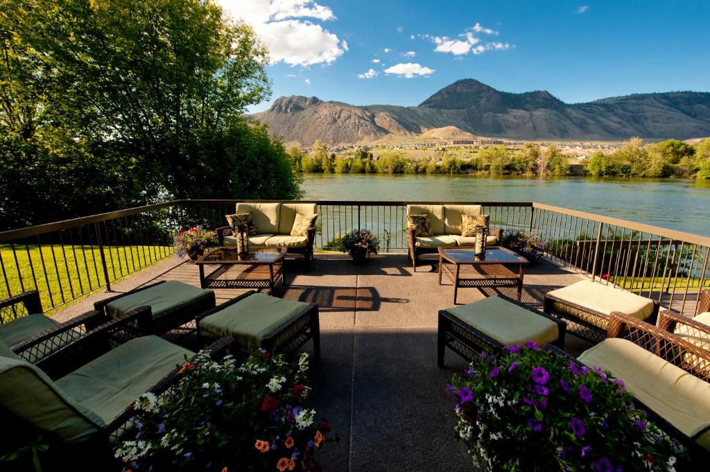 a patio with chairs and tables and a view of a river at Riverland Inn & Suites in Kamloops